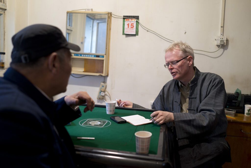 Ian Johnson interviewing pilgrimage association leader on a mahjong table.